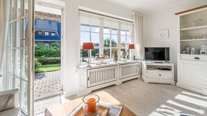 Una stanza luminosa con ampie finestre, una televisione e un'area pranzo con una candela.