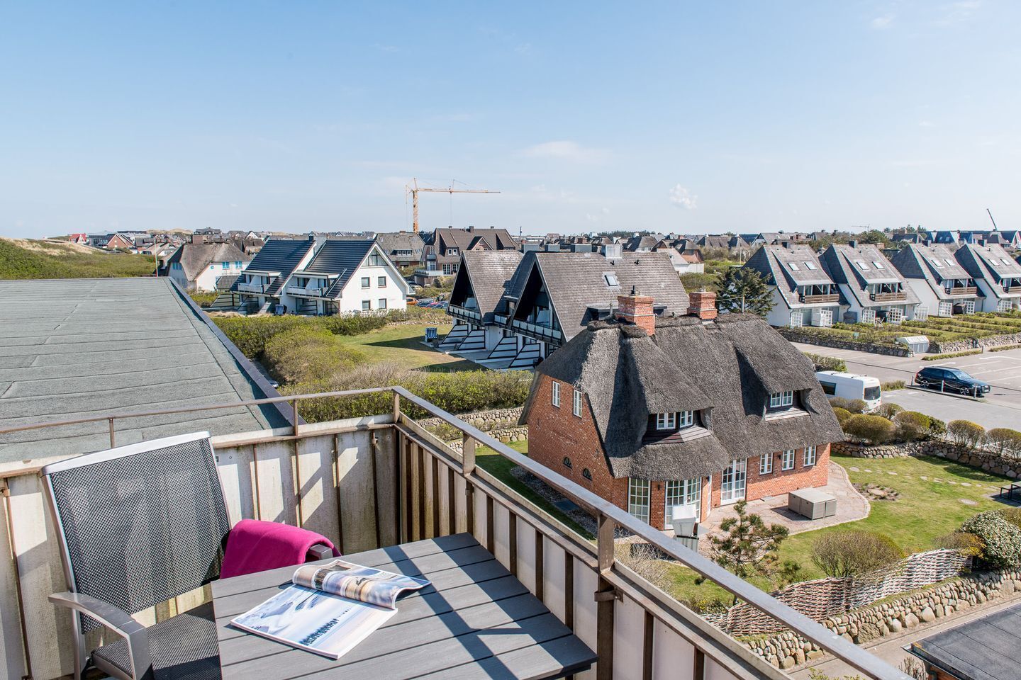 A residential area with modern houses, a construction crane, and a view of the sea.