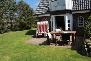 Ein Haus mit Backsteinfassade, einem Ziegeldach und einer Terrasse mit Tisch und Stühlen.