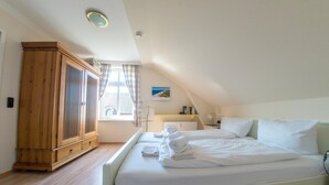 Un dormitorio con una cama grande, un armario de madera, una ventana con cortinas y un radiador.