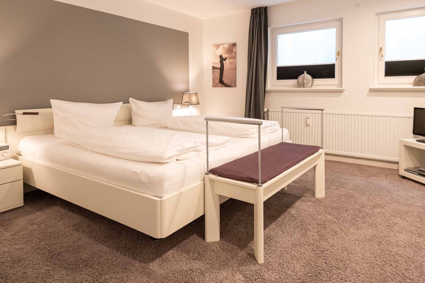 Ett hotellrum med en säng, ett nattduksbord, en lampa och ett fönster med utsikt.