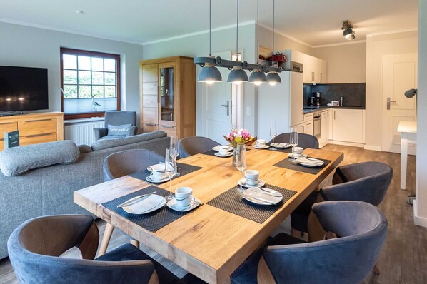 Un espace repas moderne avec une table en bois dressée pour six personnes, entourée de chaises à revêtement gris.