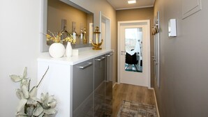 Un couloir avec un comptoir blanc, un miroir et une porte donnant sur une pièce.