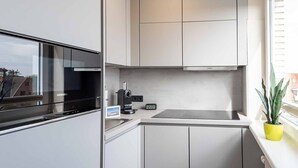 Une cuisine moderne avec des meubles blancs, un four encastré et une machine à café.