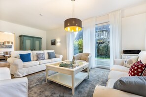 A modern living room with a white sofa set, a coffee table, and a television. - Haus Bullerbü - Helles Ferienhaus mit 6 Zimmern auf ca. 160 m², für bis zu 8 Personen (Wenningstedt-Braderup (Sylt))