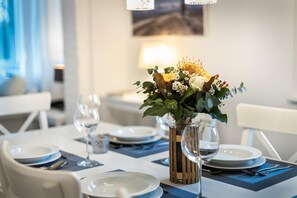 Mesa posta com pratos, talheres e um vaso de flores.