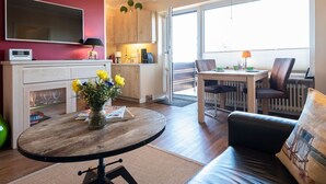 Un salon moderne avec une table ronde en bois, un canapé et un coin repas avec des chaises.