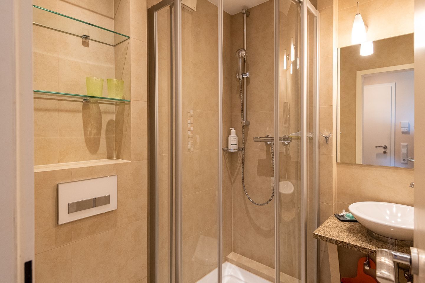 A modern bathroom with a glass-enclosed shower, a white sink, and a mirror above it.