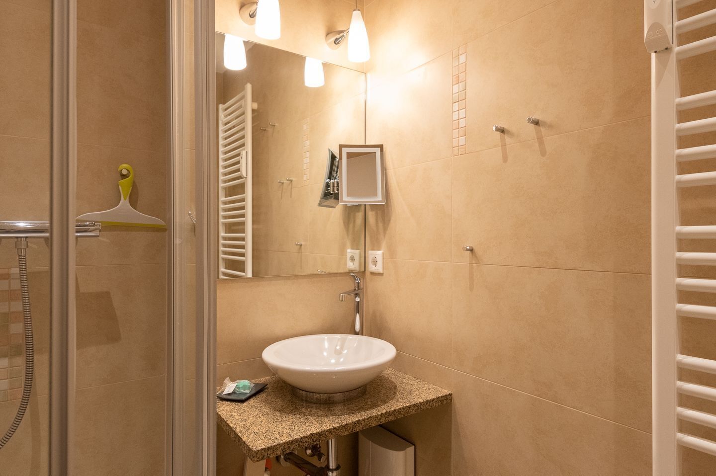 Ein Badezimmer mit einem weißen Waschbecken, einem Spiegel und einem Handtuchhalter.