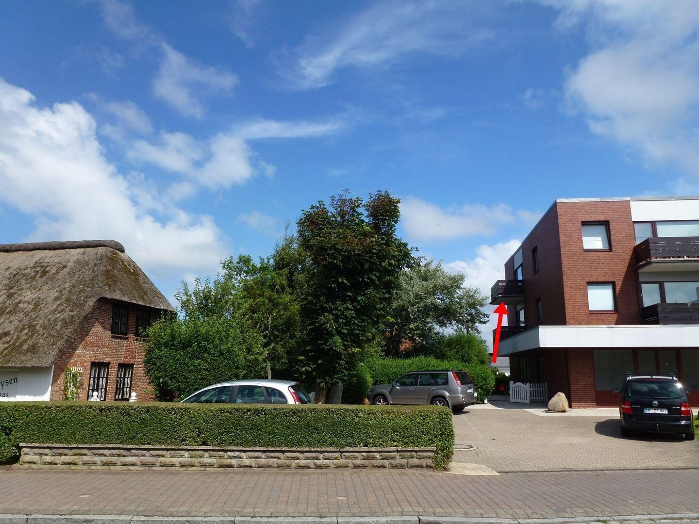 Een modern gebouw met een bakstenen gevel en een plat dak, naast een traditioneel gebouw met rieten dak.