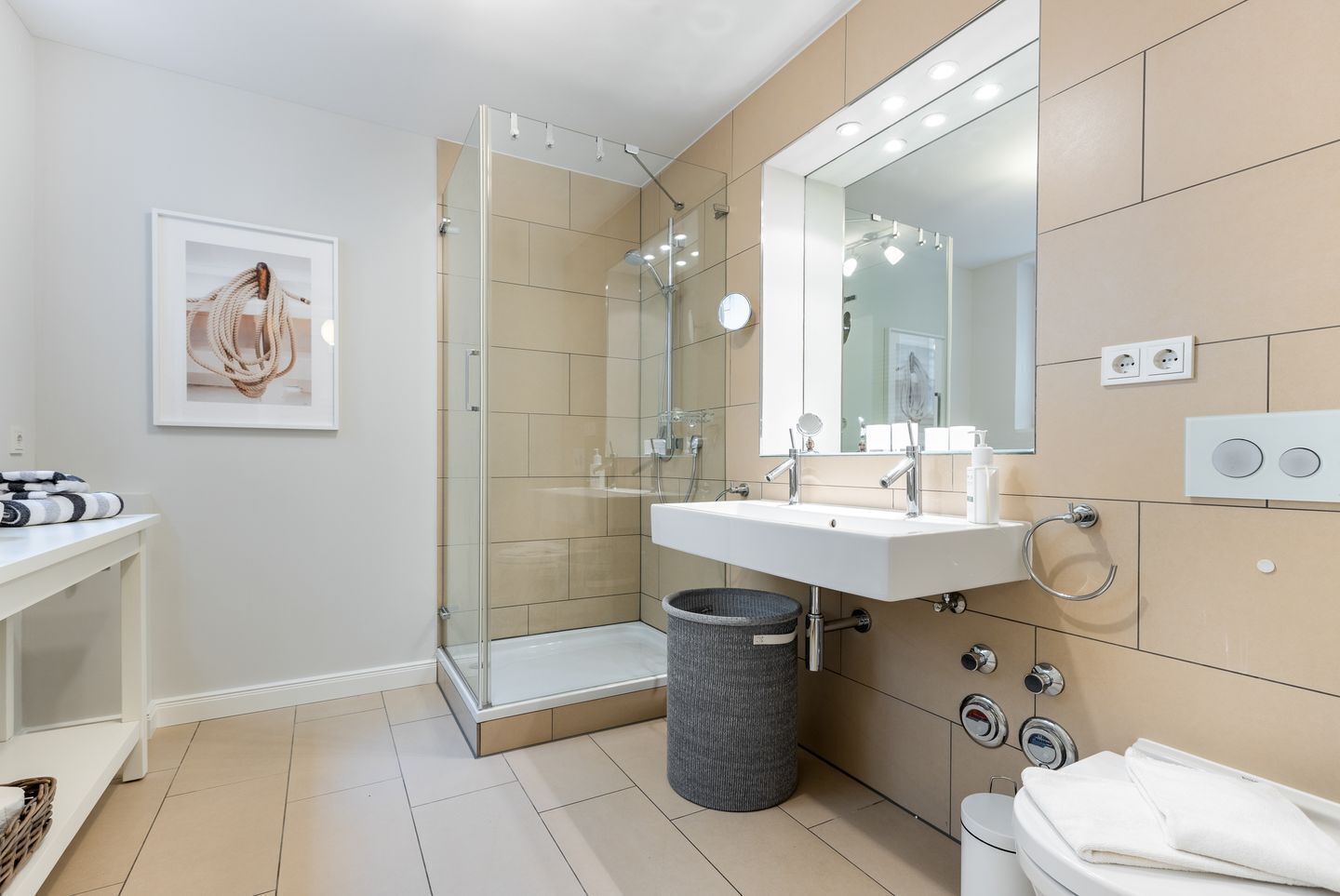 Une salle de bain moderne avec une douche à parois de verre, un lavabo blanc avec un miroir et un porte-serviettes.