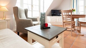 Una habitación de hotel moderna con un ventanal grande, un televisor de pantalla plana, una mesa de comedor de madera y una zona de estar cómoda.