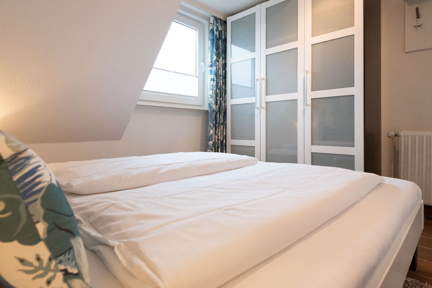 A bedroom with a bed, a window, and a wardrobe.