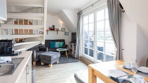 Ein modernes Apartment mit einem Wohnbereich im Loft-Stil, einer Küche mit integrierter Kaffeemaschine und großen Fenstern mit Stadtblick.