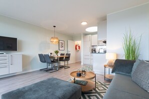 Un apartamento moderno con comedor, cocina, sala de estar y televisor.