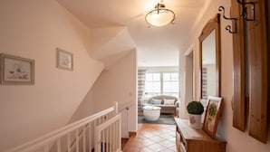 A staircase with white railings leading to a living area with a sofa and a coffee table. - LH Heidegrund, App.2 - 3-room apartment in direct beach location with approx. 75m² (Wenningstedt-Braderup (Sylt))