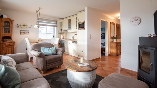 A cozy living room with a fireplace, a dining area, and a kitchen. - LH Heidegrund, App.2 - 3-room apartment in direct beach location with approx. 75m² (Wenningstedt-Braderup (Sylt))