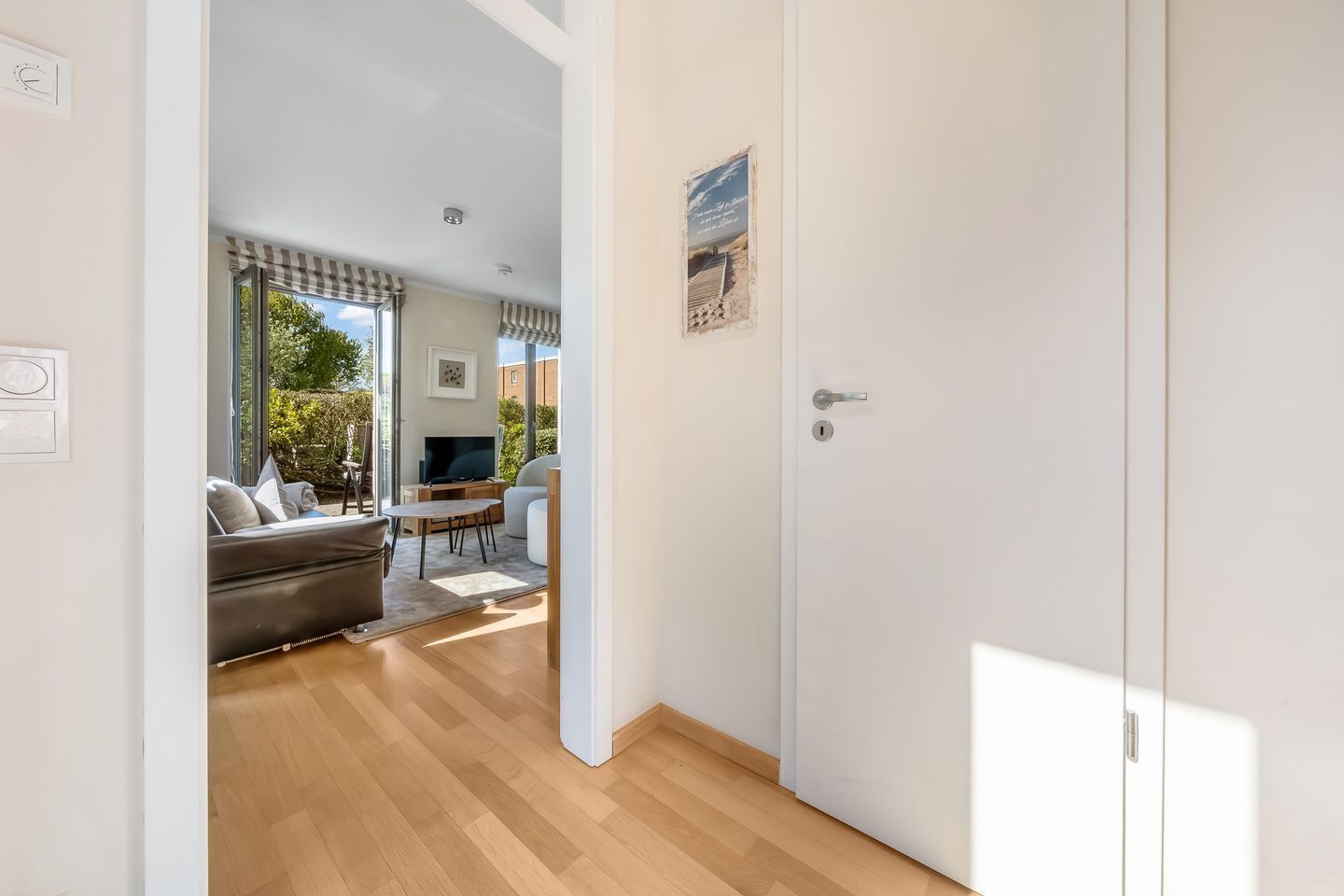 Una habitación con piso de madera, un sofá, un televisor y una mesa de comedor.