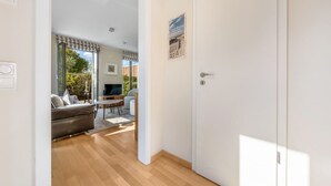 Una habitación con piso de madera, un sofá, un televisor y una mesa de comedor.