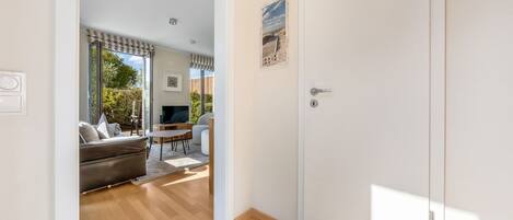 Una habitación con piso de madera, un sofá, un televisor y una mesa de comedor.