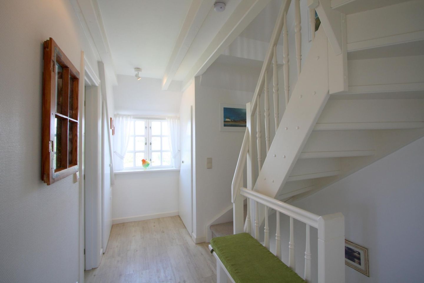 A staircase with white railings and a green bench at the bottom.