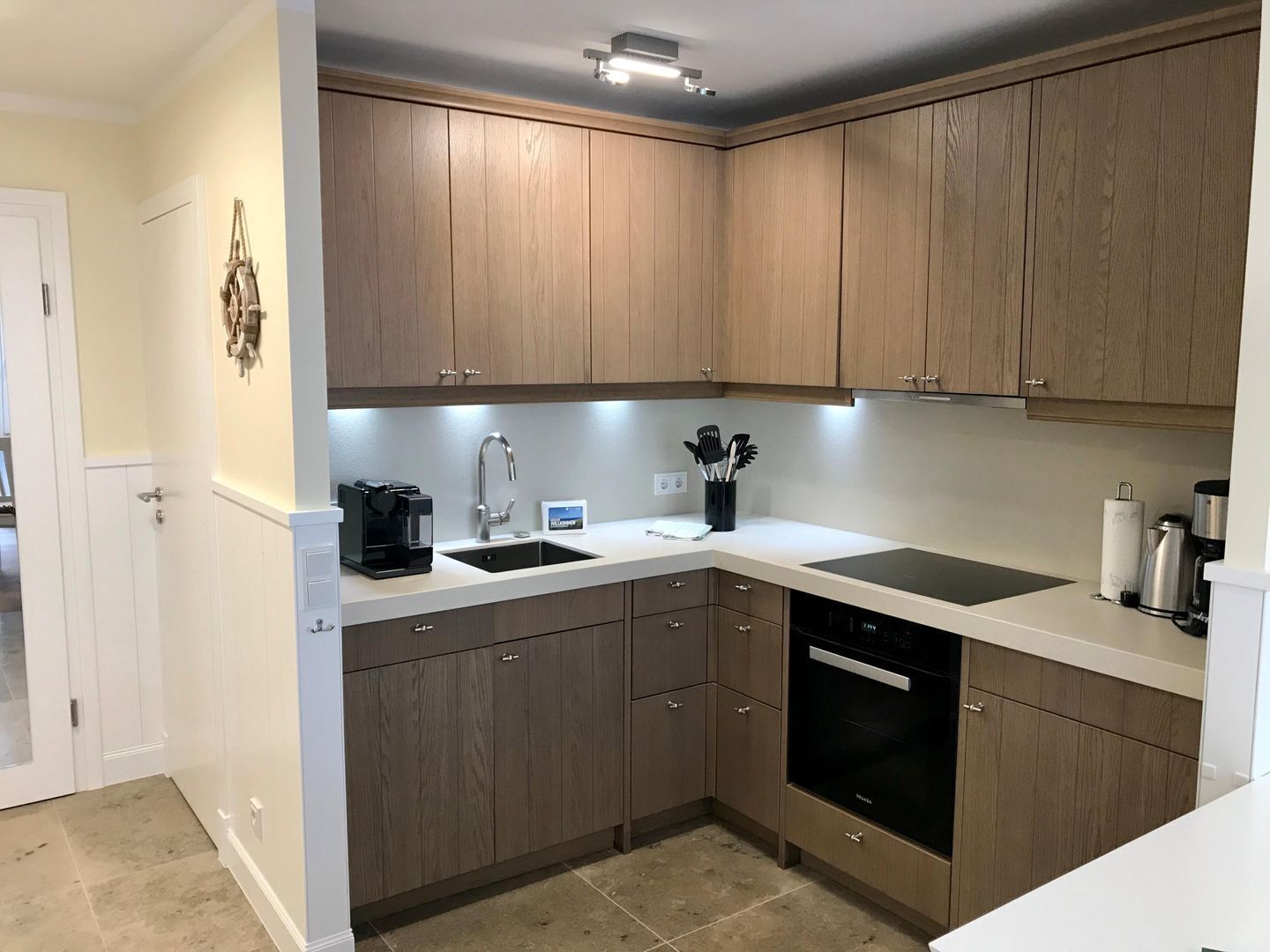 A modern kitchen with wooden cabinets, a built-in dishwasher, and a coffee maker.