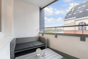 Ein Balkon mit einer Rattanbank und einem kleinen Tisch mit Dekoration.