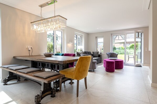 Un vaste espace de vie comprenant une grande table à manger, des sièges confortables et un lustre.