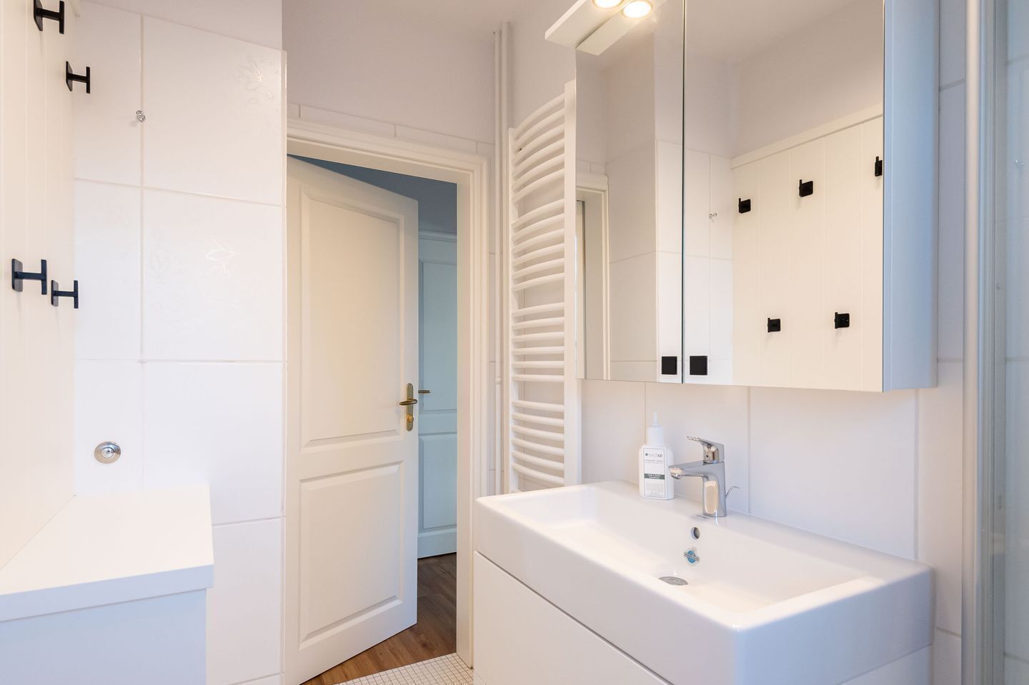 A modern bathroom with a white sink, mirror, and storage cabinets.
