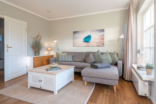Ein modernes Wohnzimmer mit einem grauen Sofa, einem weißen Couchtisch und einem Bild eines Bootes an der Wand.