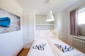 Ein Schlafzimmer mit einem Bett, einem weißen Kleiderschrank und einem Bild eines Bootes an der Wand.