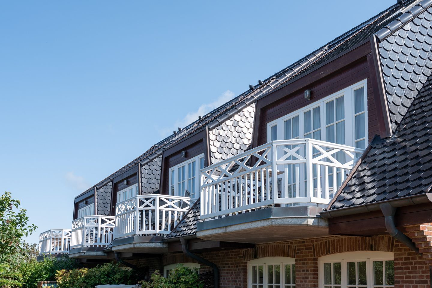 Eine Reihe von Reihenhäusern mit dunklen Ziegel-Fassaden, weißen Fensterrahmen und grauen Ziegeldächern.