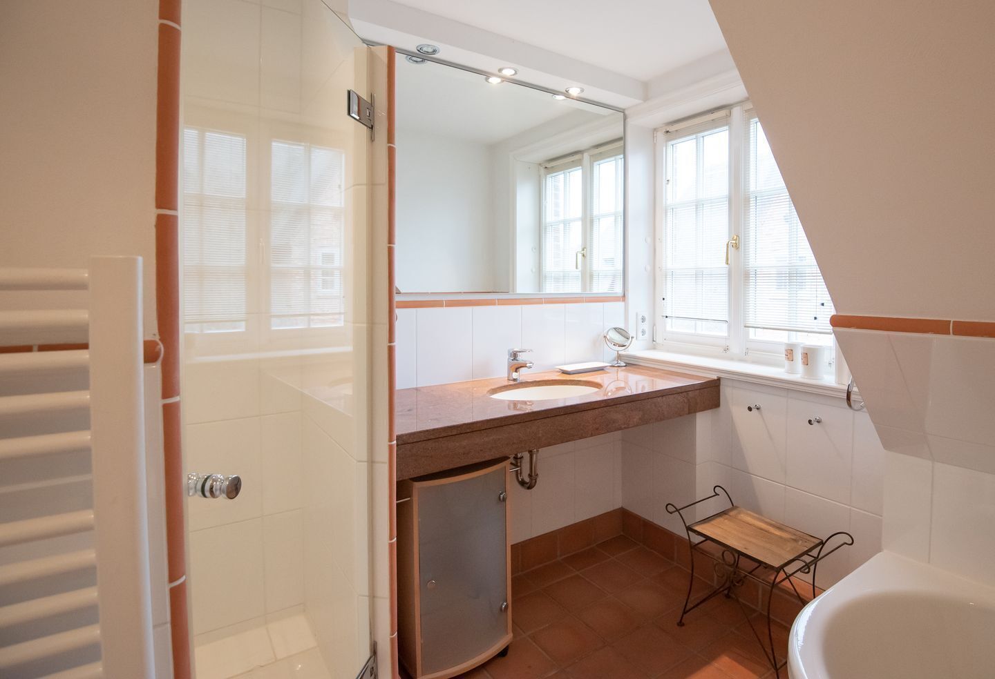A bathroom with a sink, mirror, and bathtub.