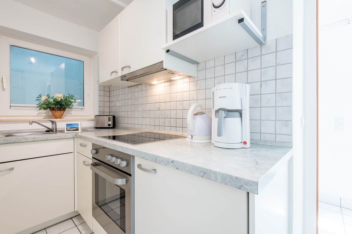 A modern kitchen with white cabinets, a built-in oven, a coffee maker, and a toaster.