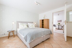 Een slaapkamer met een bed, nachtkastje, lamp, kast en uitzicht.