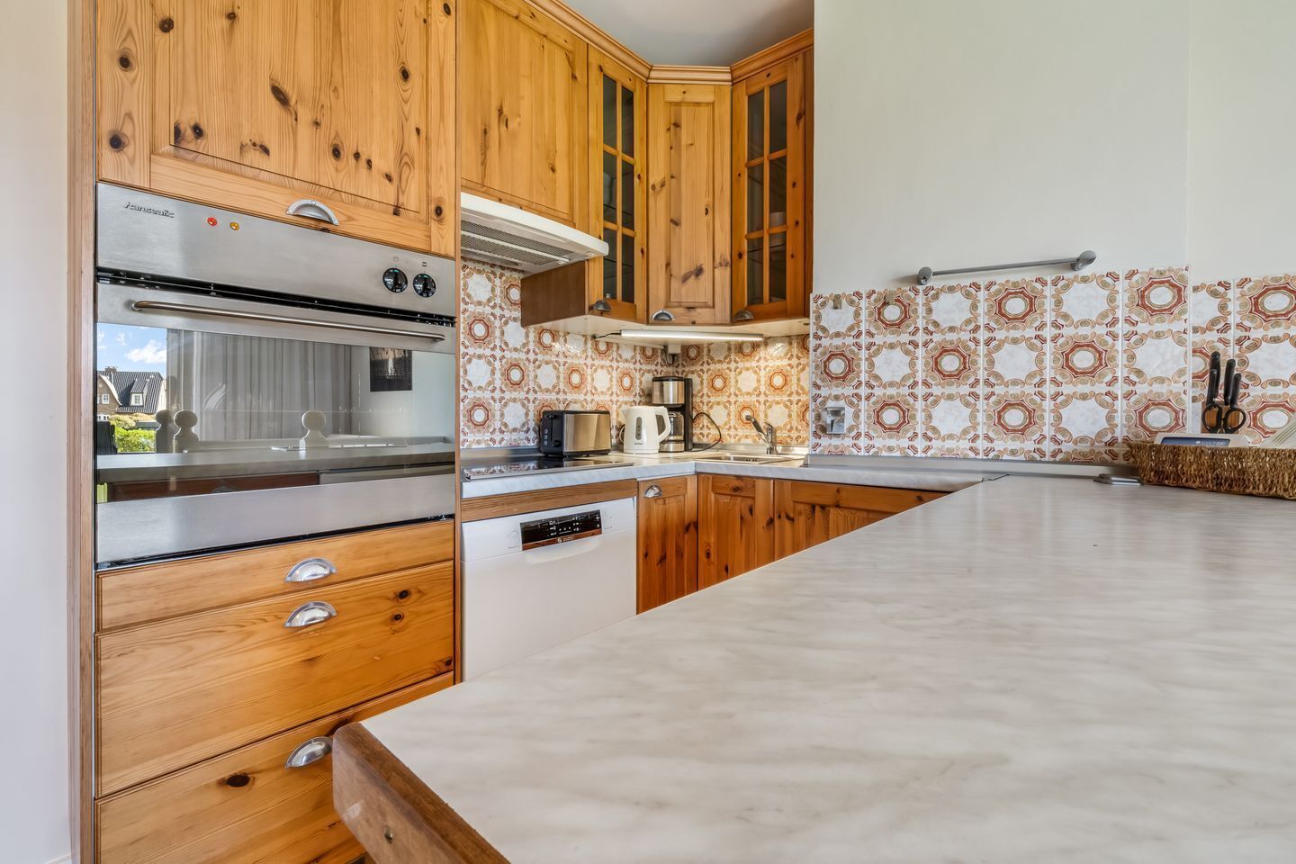 A kitchen with wooden cabinets, a built-in oven, a microwave, and a coffee maker.