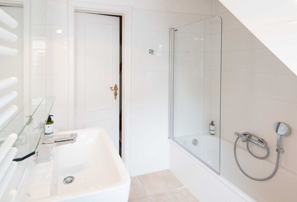 A modern bathroom with a glass-enclosed shower, a white sink, and a door with a brass handle. - Haus Gorch-fock-straße - Exklusives Hausteil mit ca. 120 m² und 5 Zimmern, für bis zu 4 Personen (Sylt)
