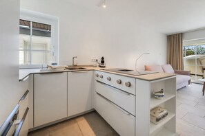 Een praktische keuken met een inbouwfornuis, een spoelbak en een raam met uitzicht op een balkon.
