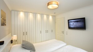 A bedroom with a bed, a TV, a bedside lamp, and a wardrobe.