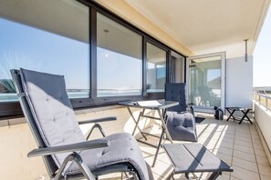 Un balcon avec deux fauteuils, une petite table et une vue sur la mer.