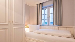 Une chambre à coucher avec un lit, une fenêtre avec des rideaux et une lampe.