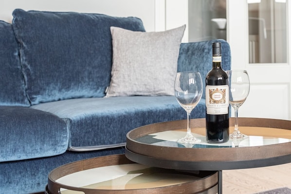 A modern living room with a blue sofa, a round wooden coffee table, and two wine glasses. - Haus Passat App. 9 - Gemütliche 1-zimmer Ferienwohnung Unter Reet mit ca. 32 m², für bis zu 2 (Wenningstedt-Braderup (Sylt))