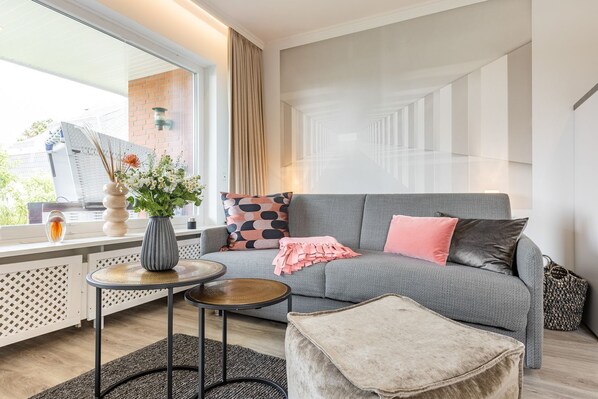 Un salon moderne avec un canapé gris, une petite table ronde et un vase décoratif orné de fleurs.