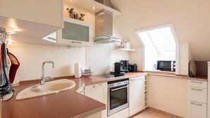 A modern kitchen with a built-in oven, a coffee maker, and a microwave. - Käpt`n Nelson, App 10 - Bright 2-room vacation apartment with approx. 52 m² living space, (Wenningstedt-Braderup (Sylt))