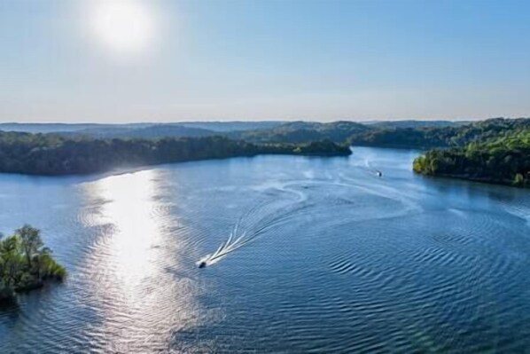 A river with a boat creating ripples. - Nolin Cabin Experience w/ Hot Tub (Grayson County)
