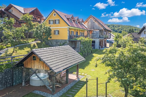 A traditional wooden building with a hot tub, surrounded by lush greenery and a clear blue sky. - Traditional House Kal With Hot tub, Semič, Slovenia (Semič)