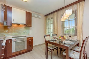 A modern kitchen with built-in appliances, a dining area with a table set for two, and a large window with curtains.