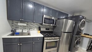 A modern kitchen with dark cabinets, stainless steel appliances, a microwave, a refrigerator, a stove, and a washing machine. - Private 1 bedroom apt in a quiet neighborhood, close to all! (Centereach)