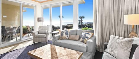 A spacious living room with a large window, a sofa, armchairs, and a coffee table.