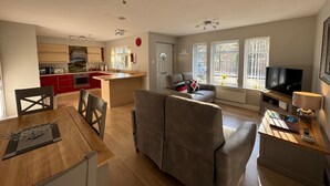A modern living space with a kitchen, dining area, and seating area. - 2 River Court, Invergarry (Invergarry)